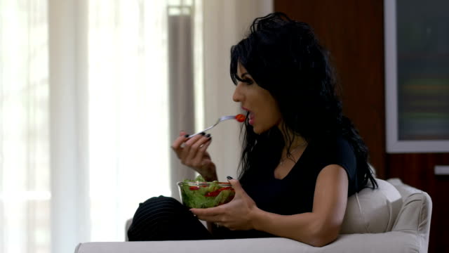 Attraktive-Frau-essen-eine-Schale-mit-Salat-und-Tomaten-Salat-Teller-vor-dem-Fernseher-zu-Hause