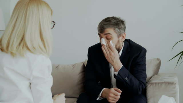 Weibliche-Psychologen-geben-Papier-Serviette-zu-weinen-Geschäftsmann-Patienten-und-beruhigen-ihn-in-ihrem-Büro