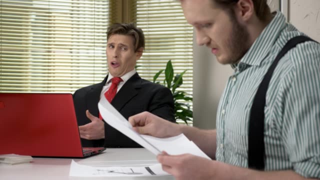 A-young-worker-makes-funny-faces-while-the-boss-does-not-see.-Parodizes-his-superior.-Work-in-the-office.-60-fps