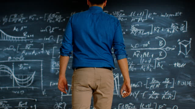 Brillante-junge-Mathematiker-nähert-sich-Blackboard-und-Oberflächen,-lange-und-komplexe-Gleichung-zu-lösen.