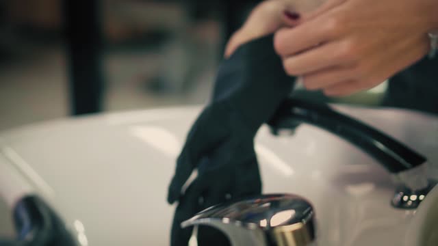 Woman-gently-pulls-black-rubber-gloves-on-her-hands-above-sink.-Closeup.-Slow-mo