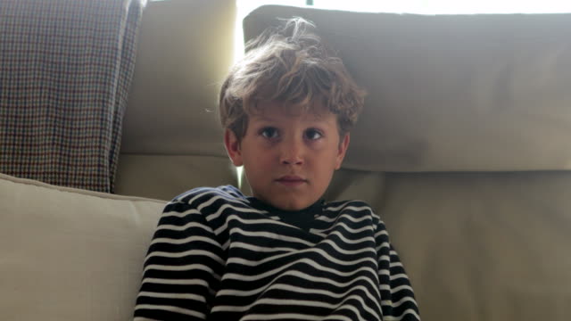 Child-face-watching-television-in-4K.-Young-boy-seated-in-sofa-starring-something-behind-viewer