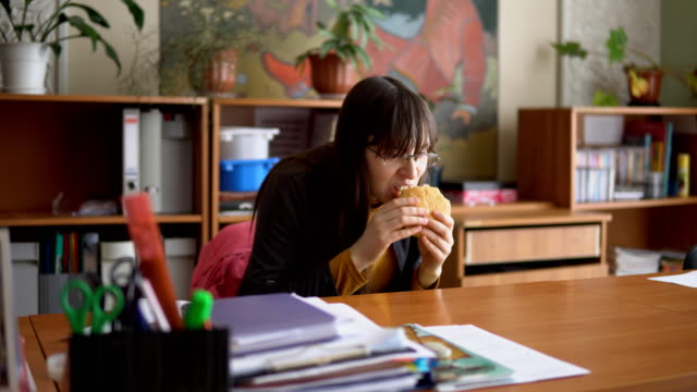 A-young-woman-in-glasses-tries-to-eat-hamburger-imperceptibly.
