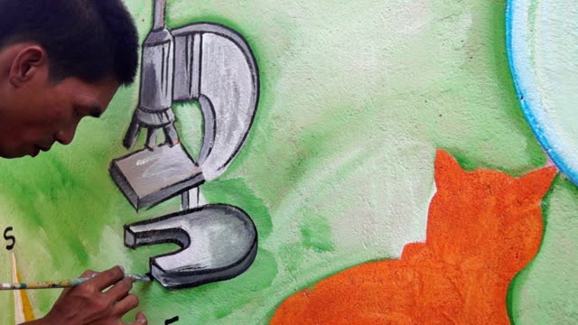 Wandmaler-zeichnet-ein-Mikroskopbild-auf-Schule-Wand.