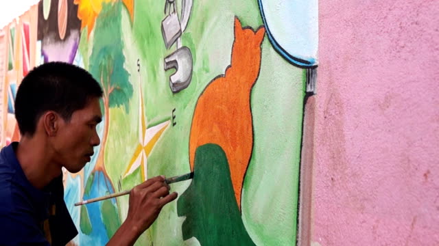 Mural-painter-draws-a-dog-image-on-school-wall.