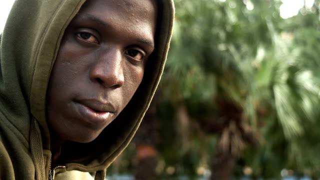 Sad-and-pensive-hooded-young-black-migrant-looking-at-camera
