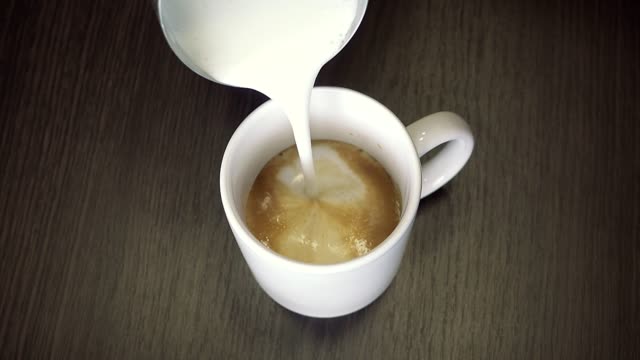 Zubereitung-von-Kaffee-mit-shaked-oben-Milch---Latte-oder-Cappuccino-in-weiße-Tasse.-Detailansicht