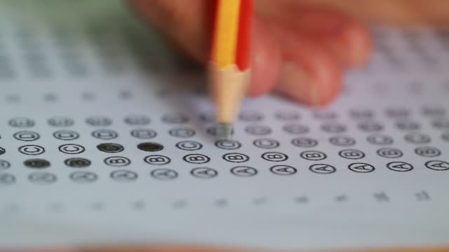 Education-students-testing-exam-with-pencil-drawing-selected-multiple-choice-quizzes-or-testing-exams-answer-sheets-exercises-in-school,-college-university-classroom