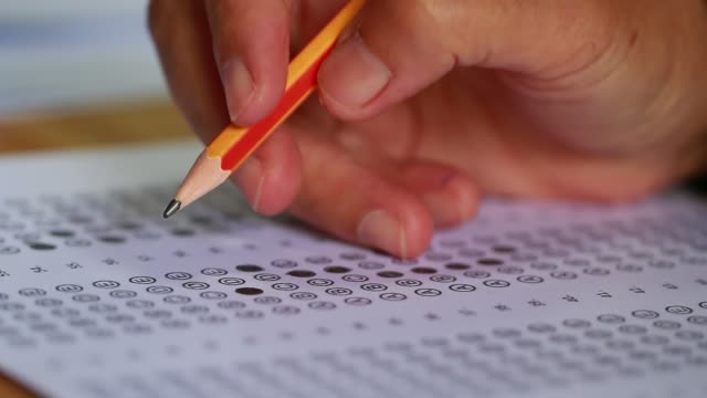 Education-students-testing-exam-with-pencil-drawing-selected-multiple-choice-quizzes-or-testing-exams-answer-sheets-exercises-in-school,-college-university-classroom