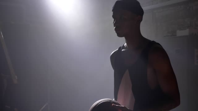 Silueta-de-jugador-de-baloncesto-africano-americano-preparándose-para-lanzar-la-bola,-de-pie-en-el-interior