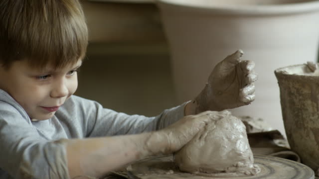 Süsser-Boy-mit-nassen-Keramik-Ton-spielen