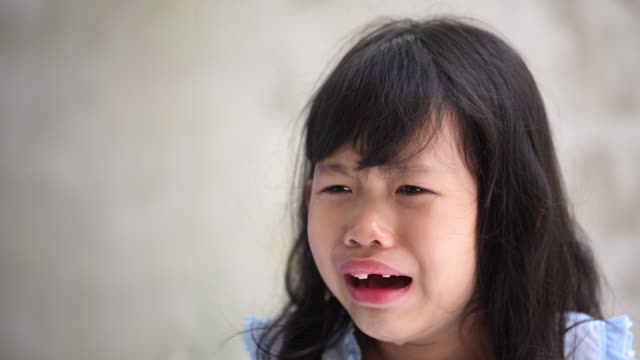 Close-up-of-Asian-Little-girl-crying-with-tears-streaming-down-her-face-from-sadness-situation