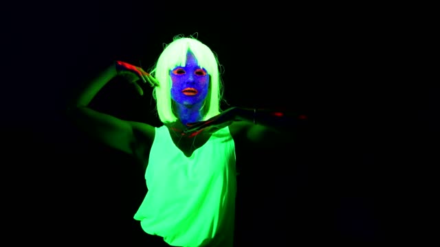 Woman-with-UV-face-paint,-wig,-glowing-clothing-dancing-in-front-of-camera,-Half-body-shot.-Caucasian-woman.-.
