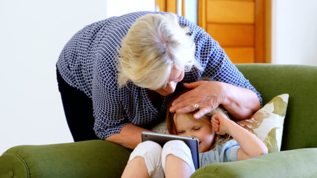 Großmutter-und-Enkelin-mit-digital-Tablette-im-Wohnzimmer-4k