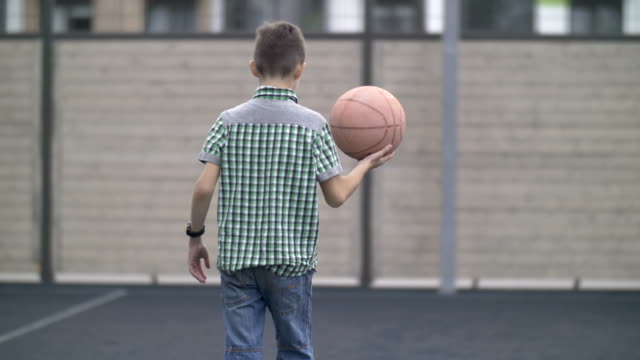 niño-está-entrenando-para-jugar-al-baloncesto,-al-aire-libre