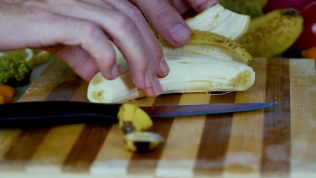 Man-setzt-eine-geschälte-Banane-auf-dem-Schneidebrett-in-Zeitlupe