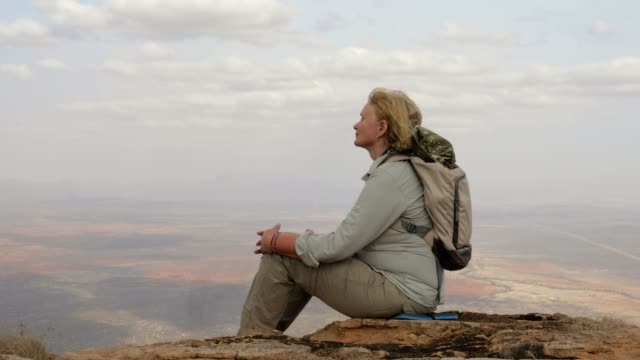 Frau-Tourist-sitzt-oben-auf-dem-Berg-und-genießt-atemberaubende-Ausblicke-und-Erfolg