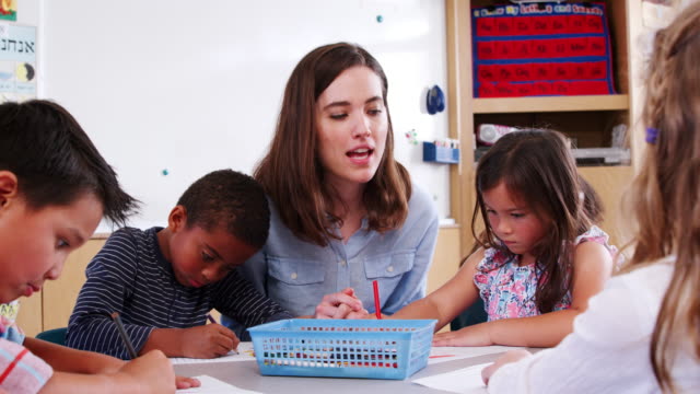 Teacher-helping-elementary-schoolchildren-in-art-class
