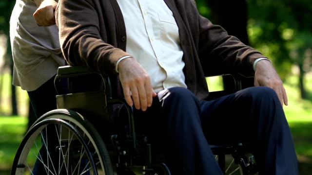 Ältere-Frau-mit-Zärtlichkeit-über-senior-Mann-im-Rollstuhl,-Unterstützung
