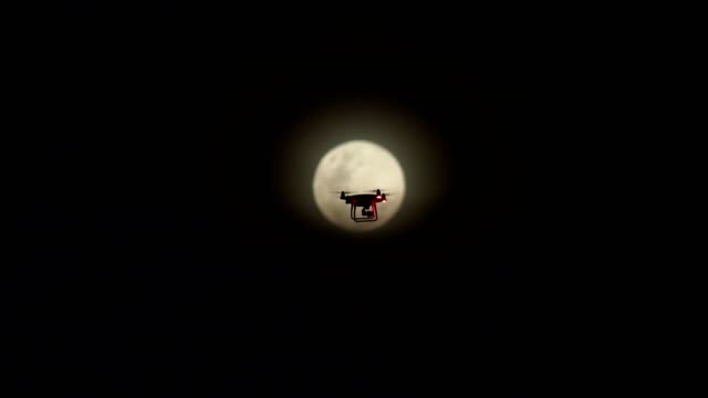 Filmmaterial-Drohne-fliegen-in-der-Nacht-mit-einem-Mond-im-Hintergrund.