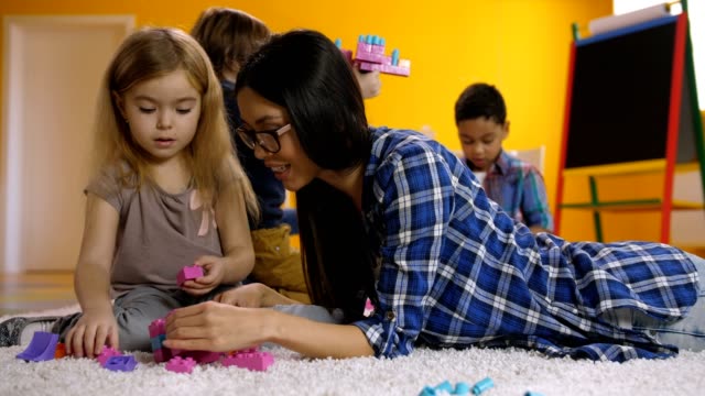 Teacher-helps-child-with-construction-toy-blocks