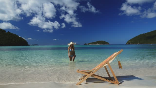 Bikini-Stroh-Hut-Frau-zu-Fuß-in-Richtung-Ufer-am-Traumstrand-in-der-Karibik