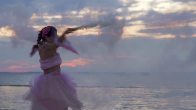 Schöne-Mädchen-mit-hellen-Make-up-in-einem-rosa-Kleid-tanzen-mit-Rauchbomben-am-Ufer-des-Flusses.-Der-Tanz-einer-sinnlichen-Frau-mit-einer-wunderschönen-Frisur-mit-Blumen.-Slow-Motion.