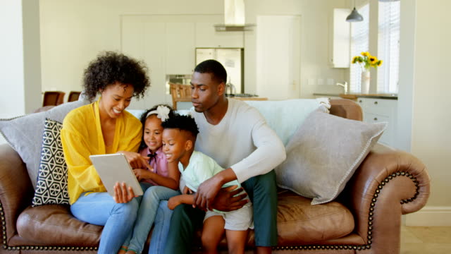 Vorderansicht-der-Familie-black-mit-digital-Tablette-im-Wohnzimmer-zu-Hause-4k