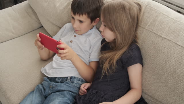 Niños-acostados-en-el-sofá-con-el-teléfono-móvil