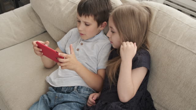 Niños-acostados-en-el-sofá-con-el-teléfono-móvil