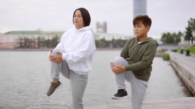 Sportliche-asiatische-Mutter-und-Sohn-arbeiten-auf-Urban-Riverside