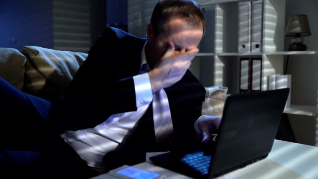 Empresario-cansado-despierta-repentinamente-y-febrilmente-trabajando-en-la-oficina-con-ordenador-portátil