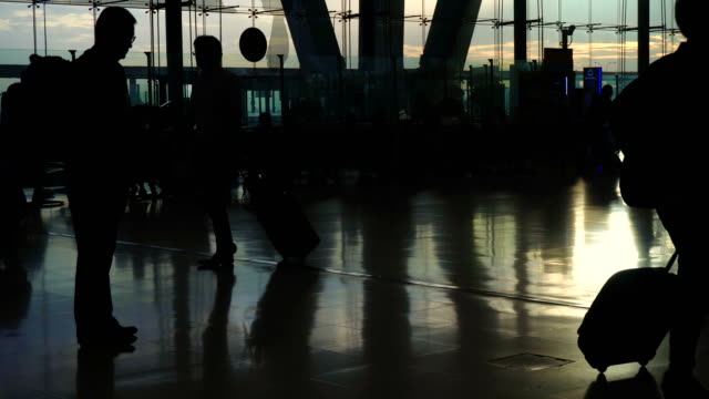 Multitud-de-silueta-de-personas-caminando-contrastan-con-la-arquitectura-de-cristal-luz-de-sol-de-la-mañana-en-el-aeropuerto