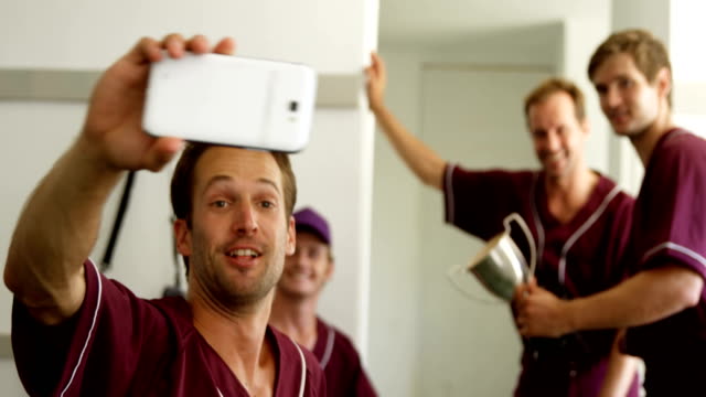 Jugadores-de-béisbol-teniendo-un-selfie-en-teléfono-móvil-en-vestidor