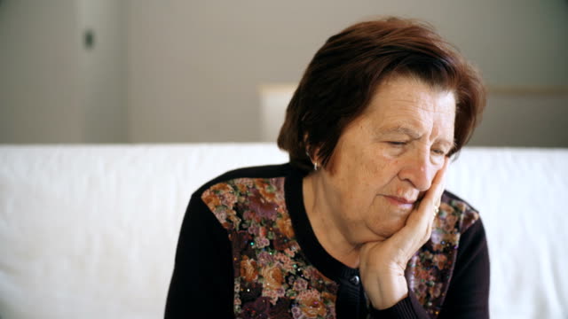 Thoughtful--worried-old-woman-on-sofa-at-home