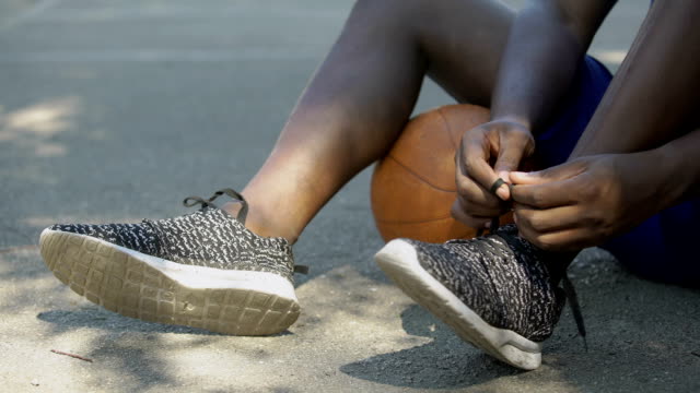 Primer-plano-de-las-piernas-del-hombre-afroamericano,-atar-cordones-de-los-zapatos-de-jugador-de-baloncesto