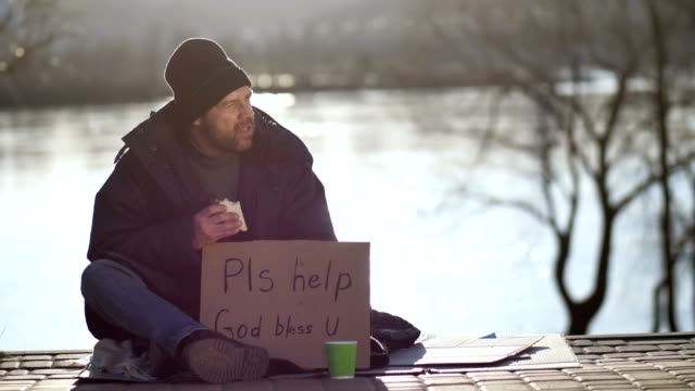 Hombre-sin-hogar-comer-sandwich-y-pidiendo-ayuda