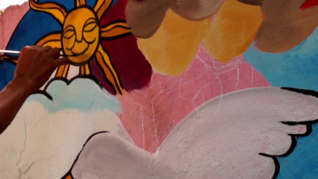Mural-painter-draws-a-sun-image-on-school-wall.