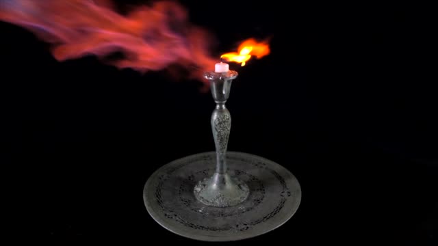 slow-motion-blowtorch-flame-thrower-on-burning-candle-in-antique-silver-holder