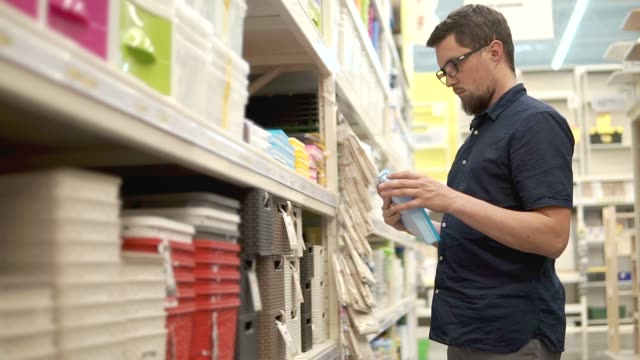 Adult-man-with-glasses-is-opening-new-plastic-container-in-a-supermarket