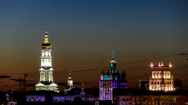 The-bell-tower-of-the-Assumption-Cathedral-Uspenskiy-Sobor,-City-council-and-house-with-a-spire-night-timelapse-in-Kharkiv,-Ukraine