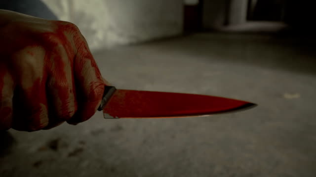Closeup-shot-of-hand-holding-a-bloody-knife-with-blood-dripping