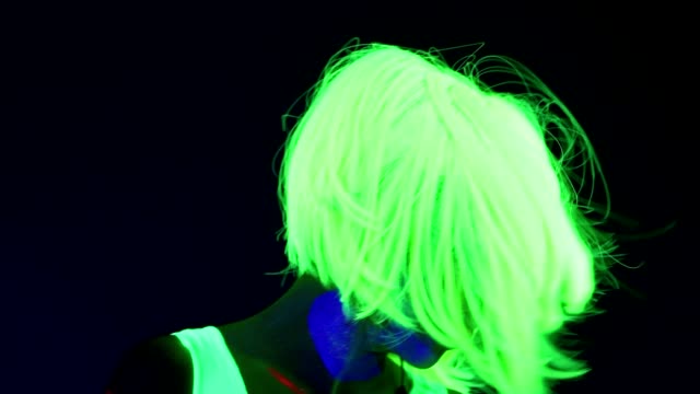 Slow-motion-of-Woman-with-UV-face-paint,-wig,-glowing-clothing-portrait-shaking-her-head.-Caucasian-woman.-.