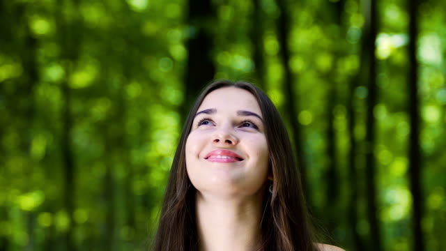 Smiling-woman-looks-up-happy-in-forest,-dreaming-feeling-joy-of-life,-happiness