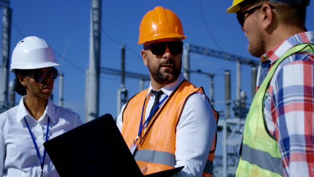 Three-electrical-workers-reviewing-documents-outside