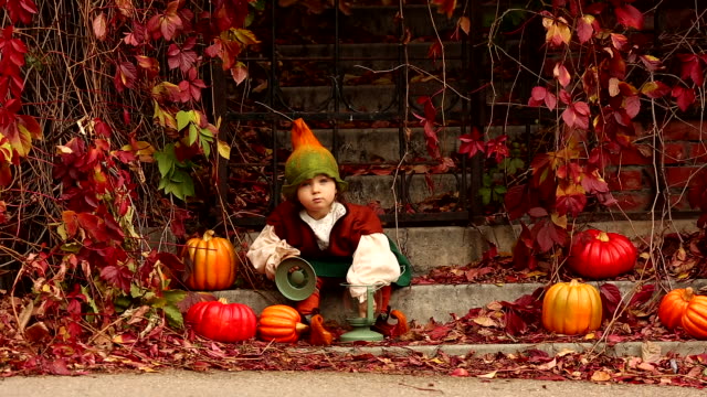 Cute-girl-in-a-gnome-costume-sitting-on-the-stairs-with-pumpkins-and-a-lantern
