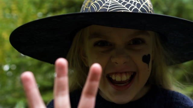 Cute-little-girl-in-witch-outfit-making-scary-faces-camera,-pretending-conjure