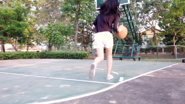 lenta-del-baloncesto-de-práctica-de-niña-en-el-patio-después-de-la-escuela