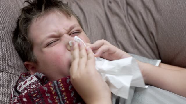 The-boy-blows-his-nose-in-paper-napkins.-He's-got-a-cold