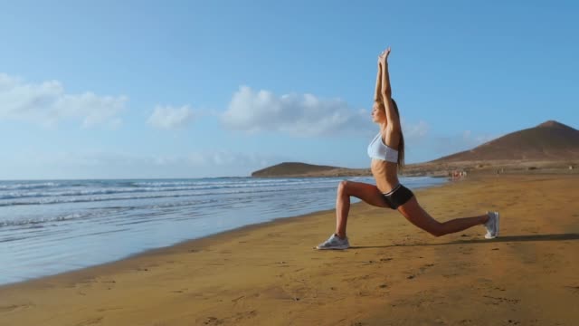 Woman-stretching-legs-and-hamstrings-doing-Standing-Forward-Bend-Yoga-stretch-pose-on-beach.-Fitness-woman-relaxing-and-practising-sport-and-yoga-on.
